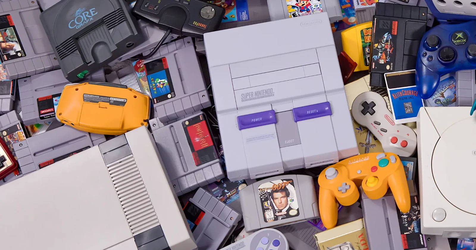 A pile of retro consoles, controllers and boxed games &mdash; SNES, Nintendo 64, GameCube, Game Boy and PlayStation &mdash; from the Save Point Shop shelves.