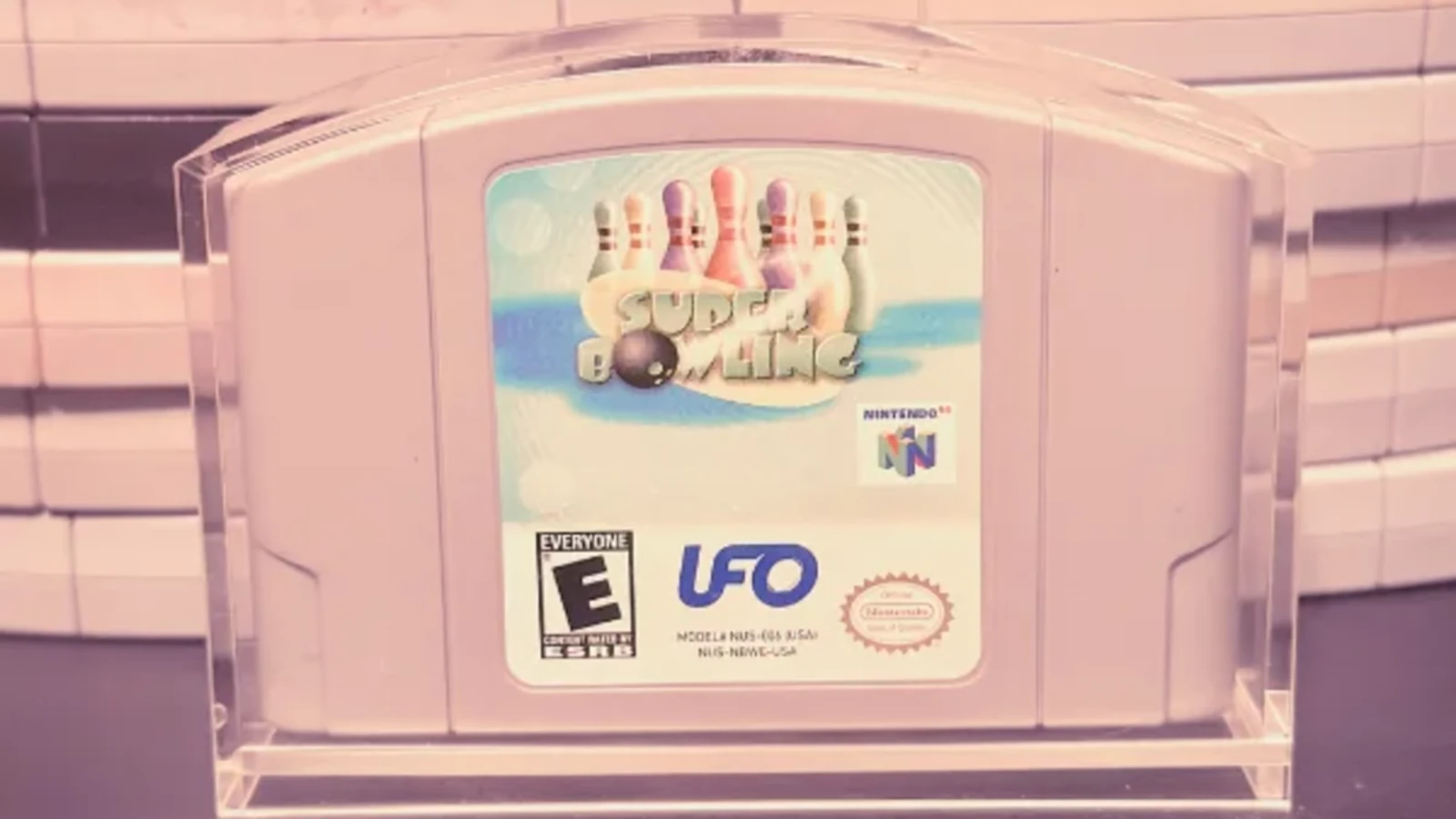A Nintendo 64 cartridge in a clear display stand in front of stacked cartridges